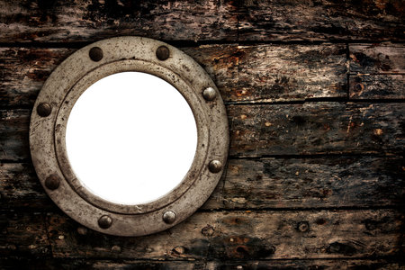 Close-up of an old rusty closed empty porthole window on old wooden planks from retro boat.の写真素材