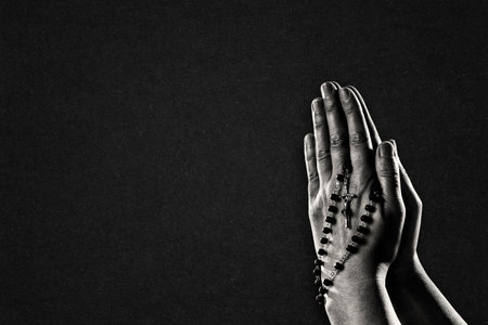 Human Hands in Black and White. Praying with a Rosary, Background with Copy Space