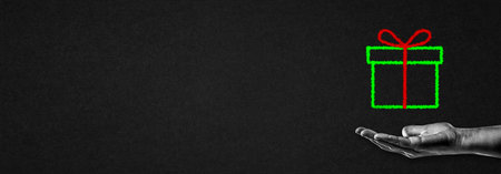 Hand in Black and White Holding Green Drawn Gift Box with Red Bow Sign on Textured Paper Background Banner, Copy Spaceの写真素材