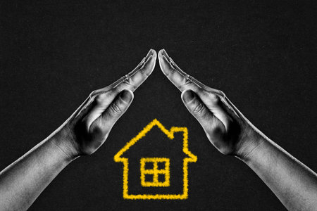 Hands in Black and White in Gesture of Protection Yellow House Symbol Sign on Black Textured Background with Copy Space. Property Insurance Conceptの写真素材