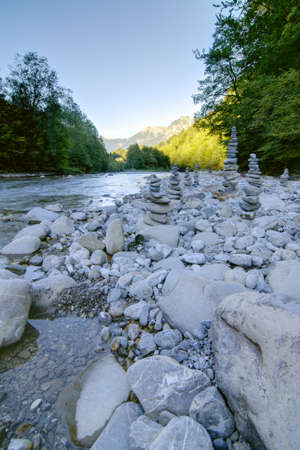 Mountain river with sunshine on the mountains and stone towers in the foreground の写真素材