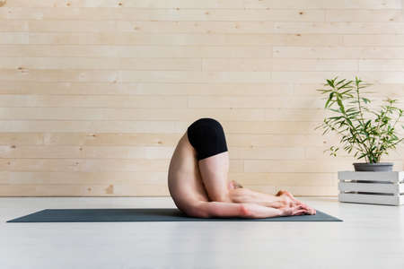 Sporty man practicing yoga, halasana, plow pose