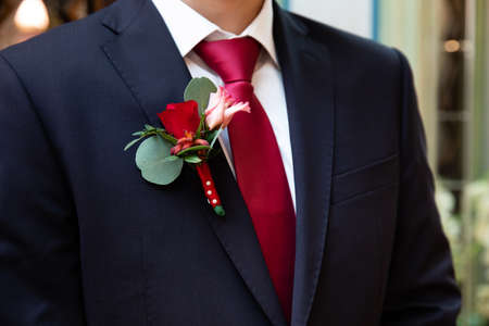 Wedding red rose boutonniere on suit of groom