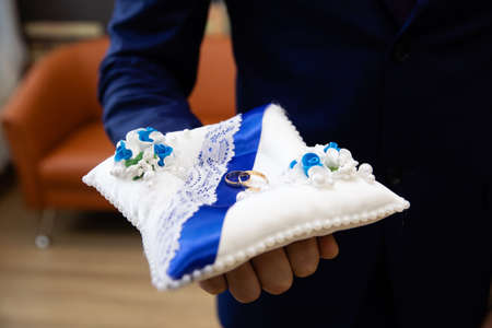 Groom holding gold wedding rings in his hands