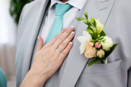 Wedding boutonniere on suit of groom and bride's handの写真素材