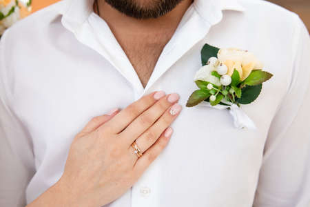 Wedding boutonniere on suit of groom and bride's handの写真素材