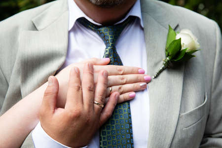 Wedding boutonniere on suit of groom and bride's handの写真素材