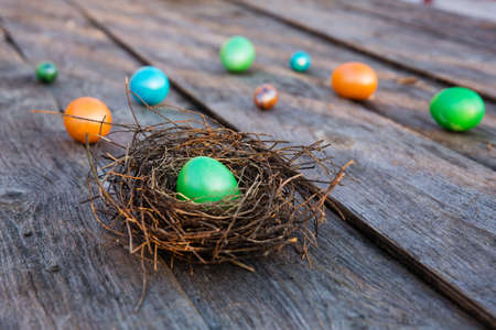 Colorful Easter eggs in the nest on wooden background