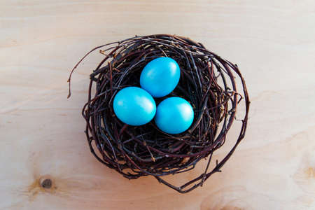 Colorful Easter eggs in the nest on wooden backgroundの写真素材