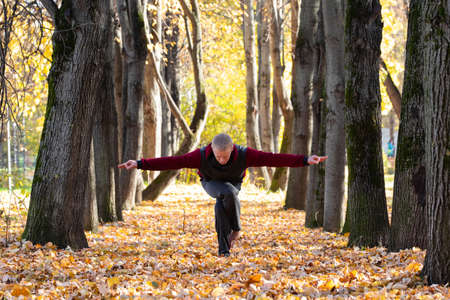 Sporty man practicing yoga in autumn parkの写真素材