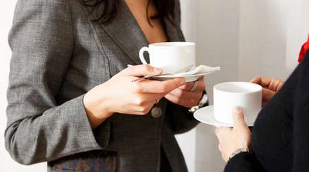 two women are drinking caffee in the officeの写真素材