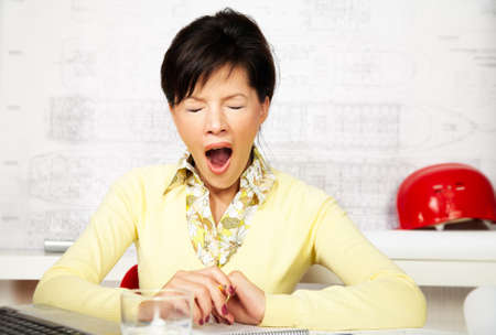 young caucasian engineer with blueprints is yawningの写真素材