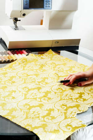 A hand of a dressmaker cutting a cloth 