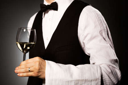 professional waiter in uniform is serving wineの写真素材