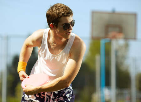 young handsome man is playing flying disc in the park