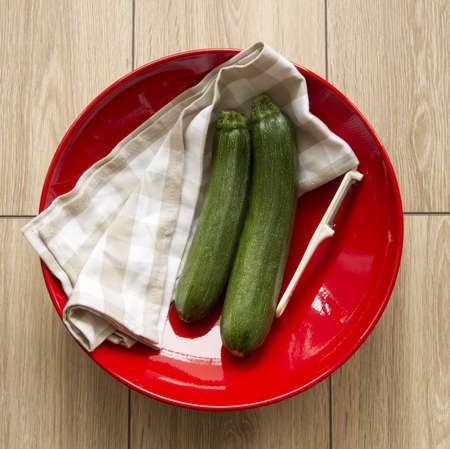 pair of green zucchini on red plateの写真素材