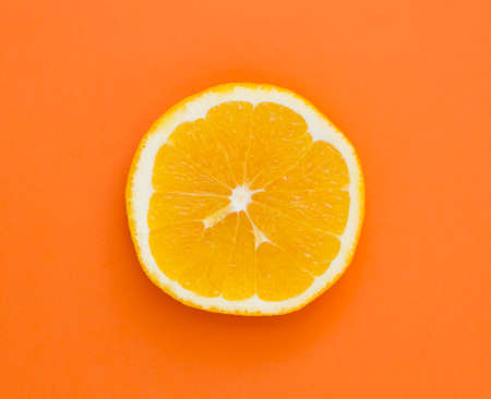 single slice of fresh orange on orange backgroundの写真素材