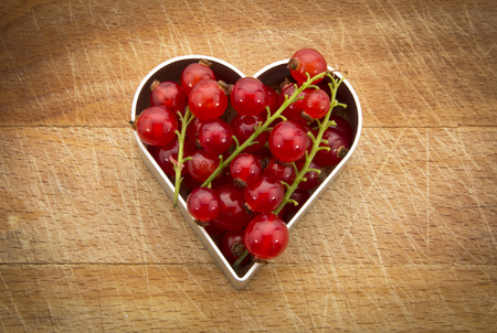 fresh currants in heart shape on wooden backgroundの写真素材