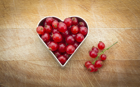 fresh currants in heart shape on wooden backgroundの写真素材