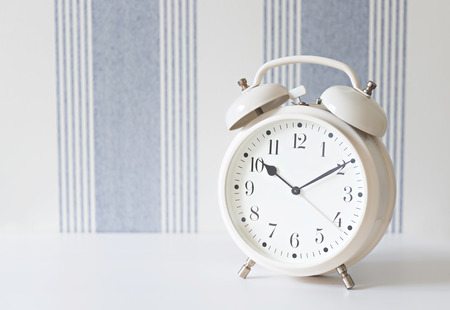 retro white alarm clock on white table, copy spaceの写真素材