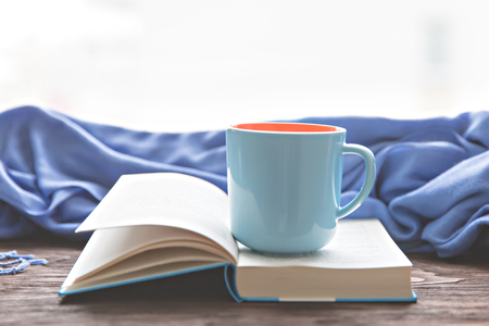 cup warm beverage on the opened bookの写真素材