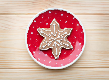 Gingerbread cookie on the red plate on the wooden background.の写真素材