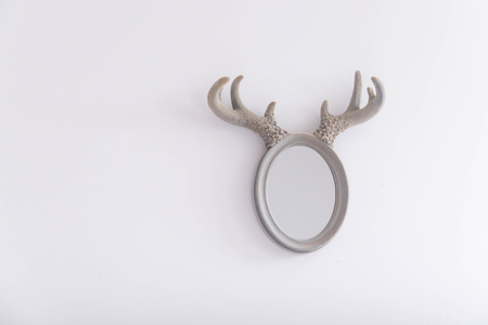 Oval mirror with horns on the white painted wallの写真素材