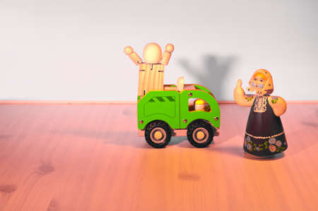 A woman wearing a scarf and a doll screaming with arms stretched out on a wooden truck.の写真素材