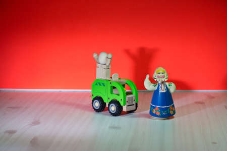 A woman wearing a scarf and a doll screaming with arms stretched out on a wooden truck.の写真素材
