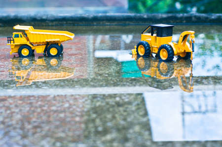 There are toy trucks and forklifts in the water above the cement floor.の写真素材