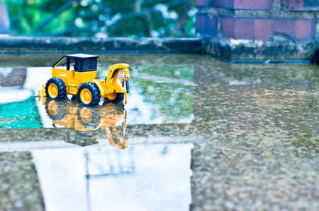 There is a toy forklain in the pavement next to a brick pillar.の写真素材