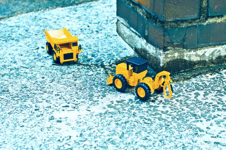 There are toy trucks and forklifts next to brick pillars.の写真素材