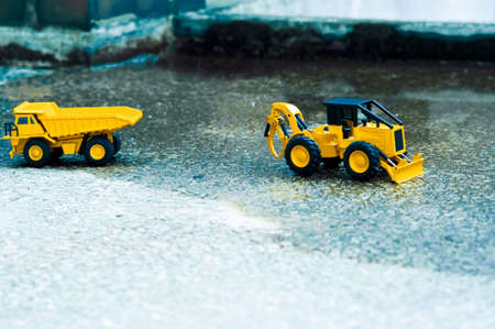 There are forklifts and truck toys next to waterlogged cement and old brick pillars.の写真素材