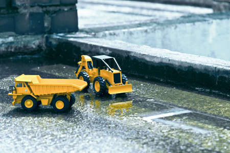 There are forklifts and truck toys next to waterlogged cement and old brick pillars.の写真素材