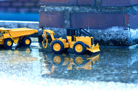 There are forklifts and truck toys next to waterlogged cement and old brick pillars.の写真素材