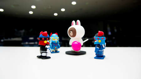 A white bear with a pink candy on a dark stage with a robot guards wearing blue helmets