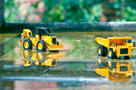A folklore toy car projected onto a cinder with a bit of water on a bright spring day.の写真素材