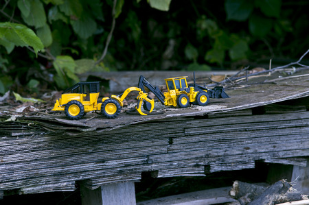 Two forklift toy cars on a wide wooden plank stimulate our concentricity.の写真素材