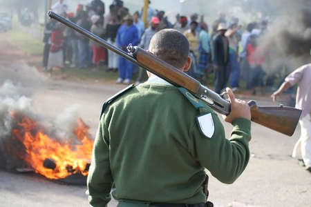 Security guard watching an angry protesting crowd of people