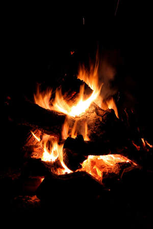 Glowing embers and flames of a camp fire at nightの写真素材