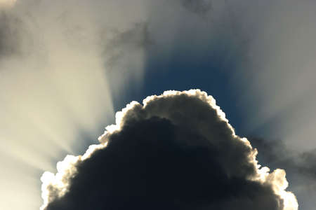 Billowing clouds and suns rays shining behindの写真素材