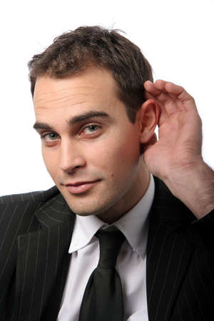 Young business executive cupping hand behind ear on white backgroundの写真素材