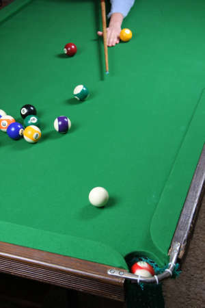 Sinking a ball during a pool game on a felt covered table