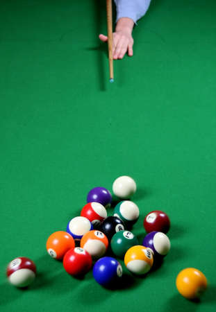 Pool balls being broken by a player whose hand and cue is visible