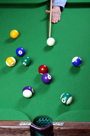 Pool player shooting to sink a ball in the middle pocket