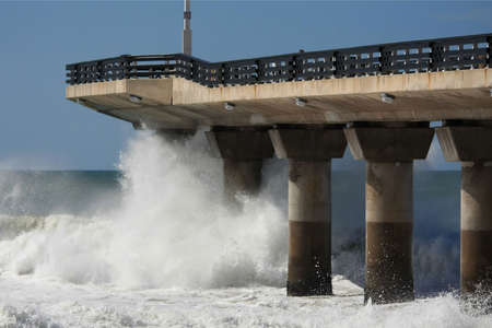 Big ocean waves crashing into the end of a pier at the frontの写真素材