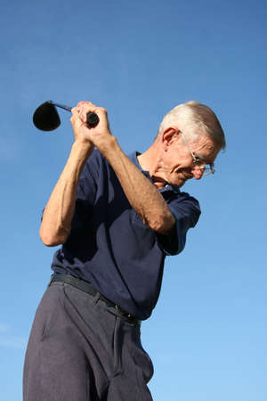 Senior golfer about to strike the ball with his driver clubの写真素材