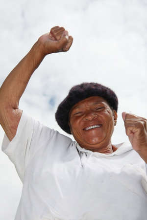 Happy african woman with smile and raised armsの写真素材