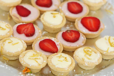 Plate of scrumptuous cream and stawberry cup cakesの写真素材