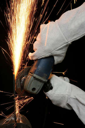 Shower of orange sparks from a worker grinding steelの写真素材